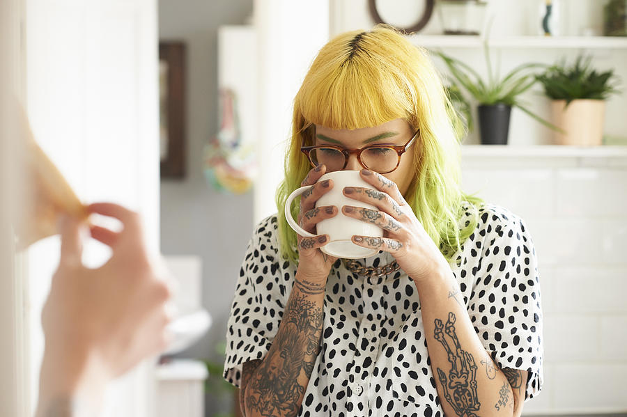 Young hipster woman drinking from a mug in her kitchen Photograph by Richard Drury
