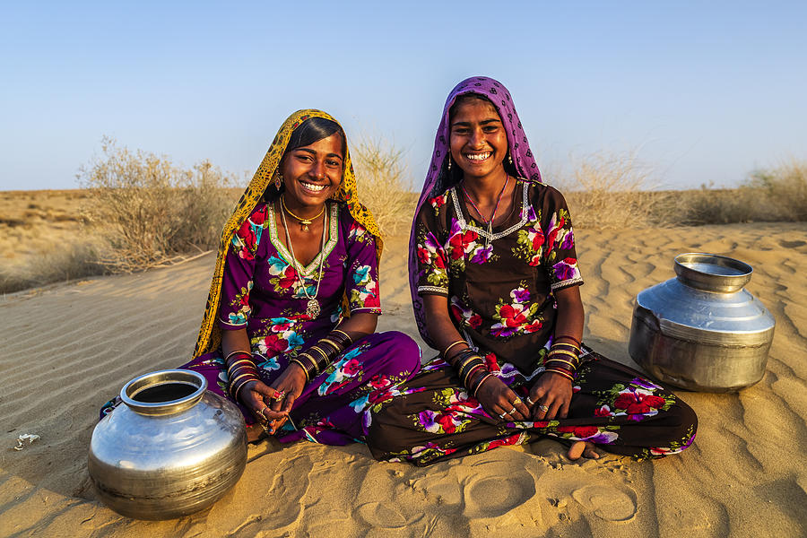 Young Indian girls carrying water from well, desert village, India Photograph by Hadynyah