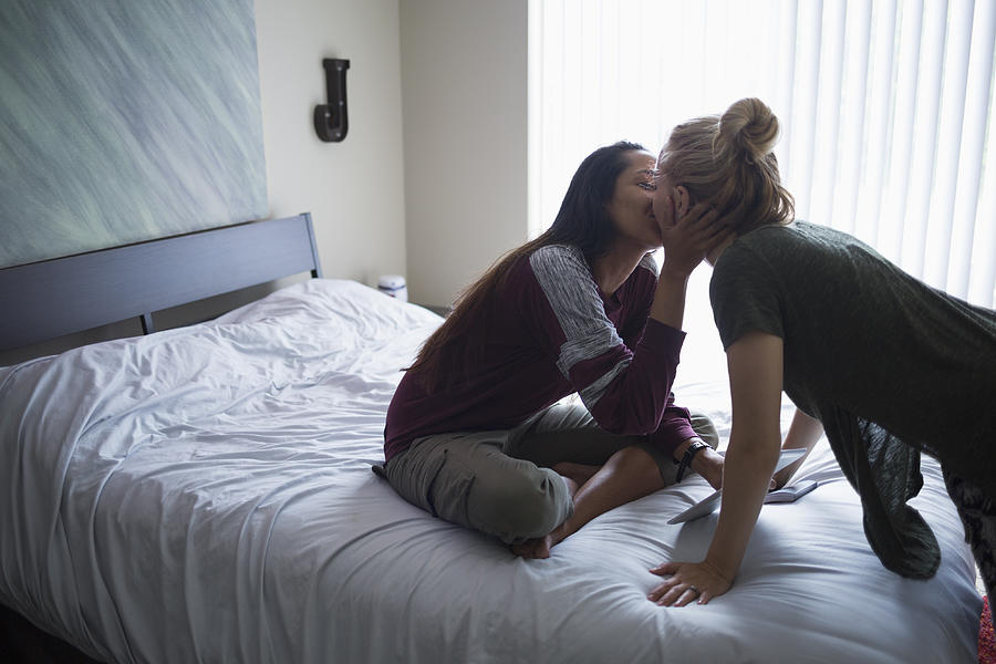 Young lesbian couple kissing on bed at home Photograph by Nolwen Cifuentes