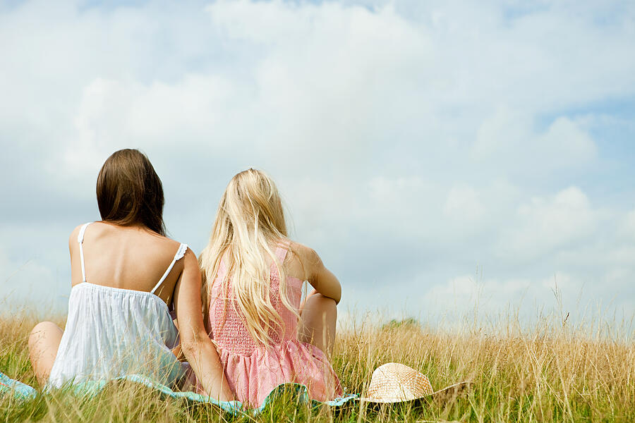 Young lesbian couple sitting together in countryside Photograph by Image Source
