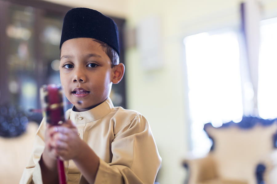 Young Malaysian boy in traditional clothing playing with his toy . Photograph by GCShutter
