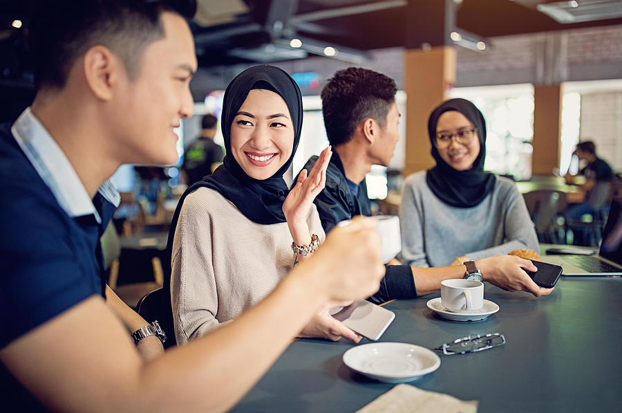 Young Malaysian couples are talking and drinking coffee in a cafeteria Photograph by Praetorianphoto