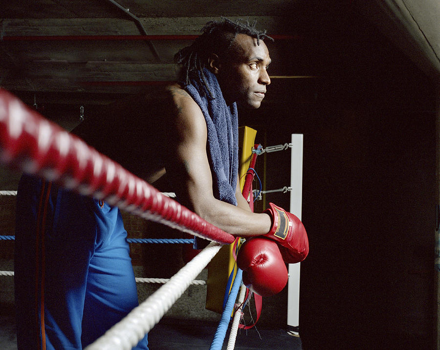 Young male boxer arms crossed resting on ring side, looking ahead Photograph by Janie Airey