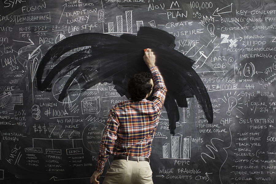 Young male erasing business plans on blackboard Photograph by Justin Lewis