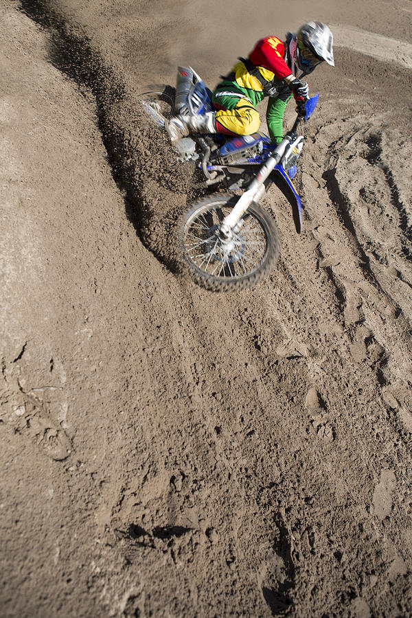 Young male motocross rider racing down mud hill Photograph by Zero Creatives
