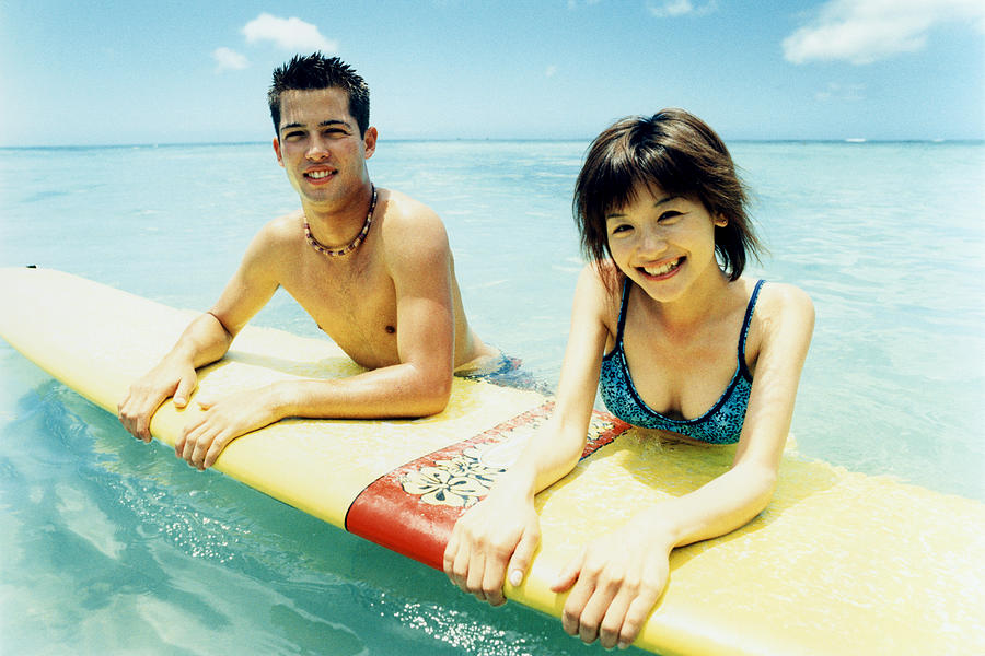 Young man and woman on surfboard in water Photograph by Dex Image