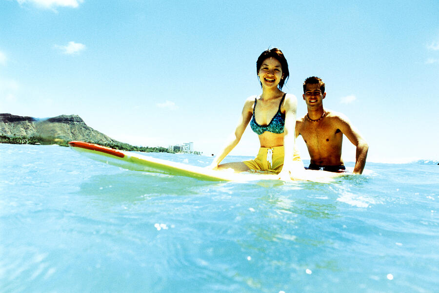 Young man and woman sitting on surfboard in water Photograph by Dex Image
