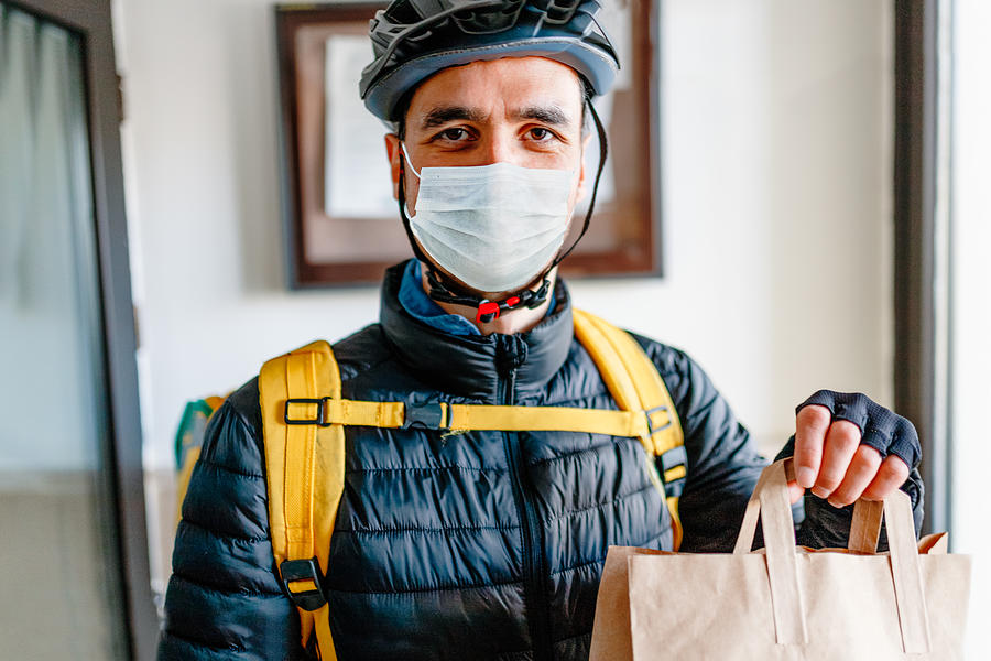 Young man as a courier delivering  food Photograph by Phynart Studio