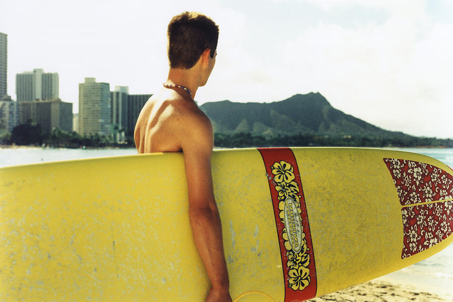 Young man at a beach, holding surfboard Photograph by Dex Image