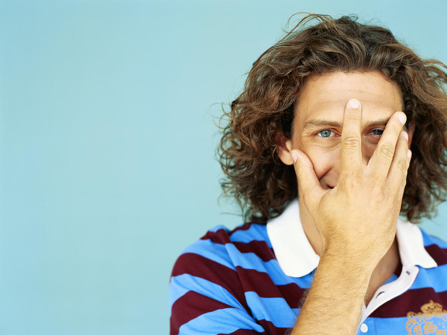 Young man covering face with hand, close-up Photograph by Stockbyte