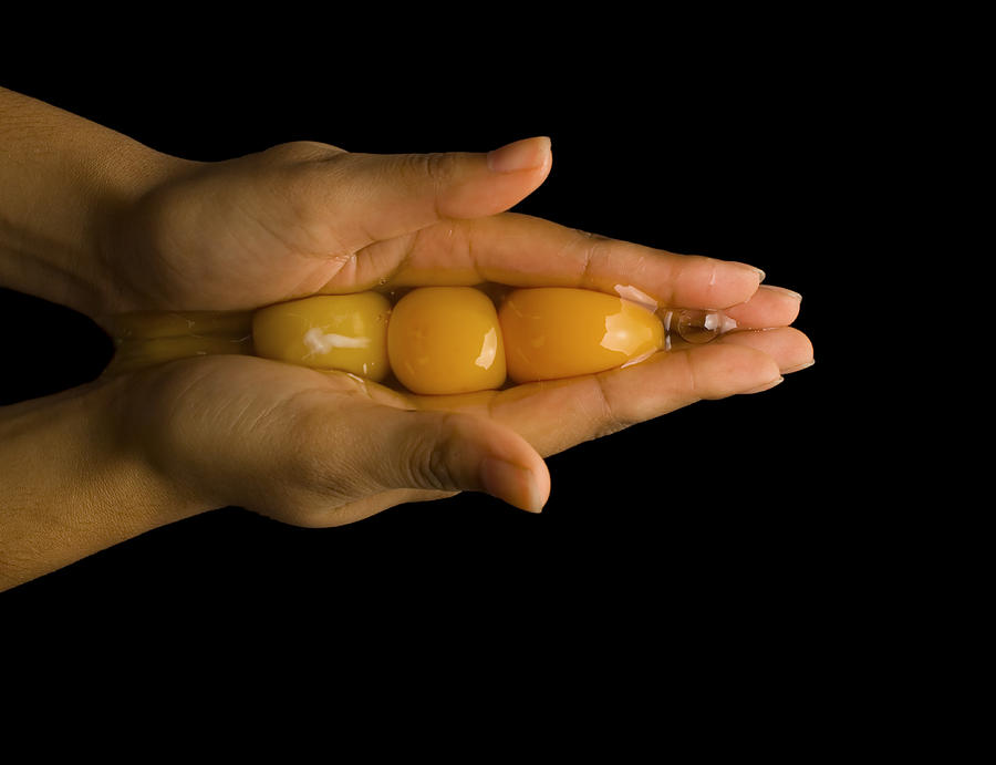 Young man cupping three egg  yolks in hand, close-up of hand Photograph by Howard Kingsnorth