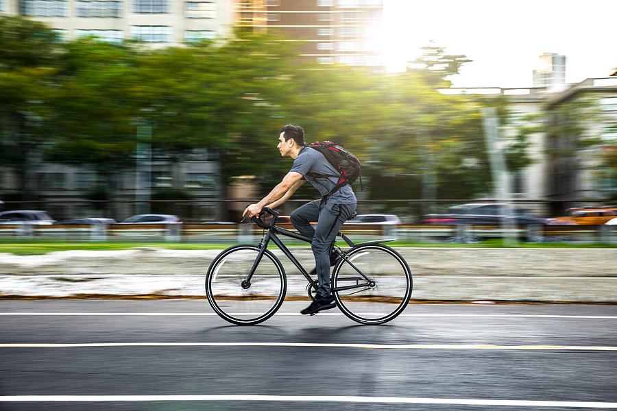 Young man cycling in the city, commuting to work Photograph by LeoPatrizi
