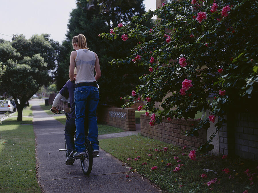 Young man cycling with young woman on back of bike, rear view Photograph by Dex Image