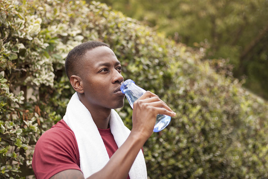 Young man drinking water after exercise Photograph by Kelvinjay