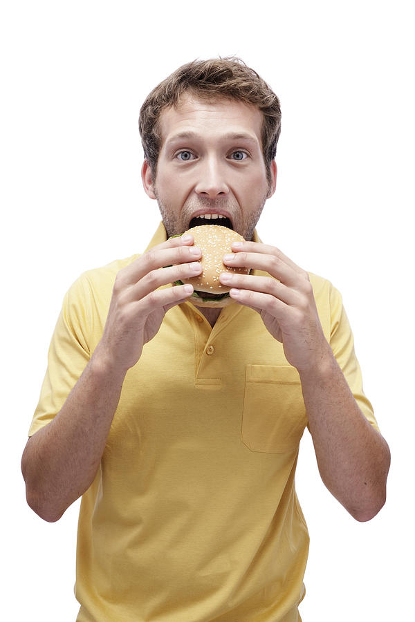 Young man eating Hamburger, portrait Photograph by Michael Bader