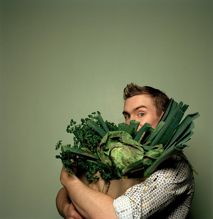 Young man holding bag full of vegetables, portrait Photograph by Betsie Van der Meer