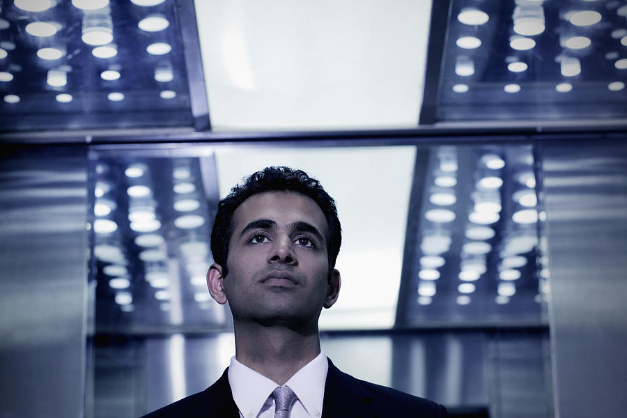 Young man in business suit standing in elevator Photograph by Alex Mares-Manton