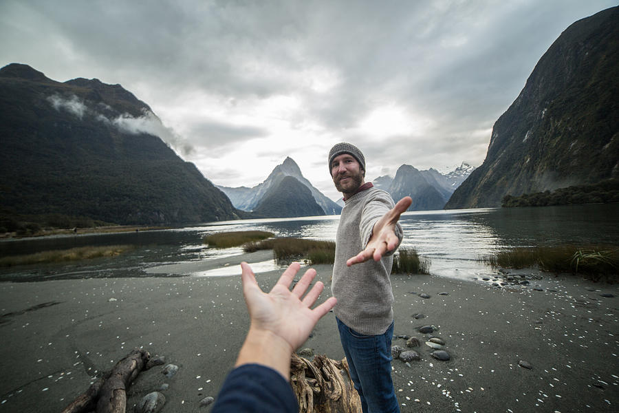Young man in nature offers hand to partner Photograph by Swissmediavision