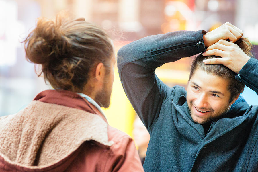 Young man influenced by friend to make a man bun Photograph by NicolasMcComber