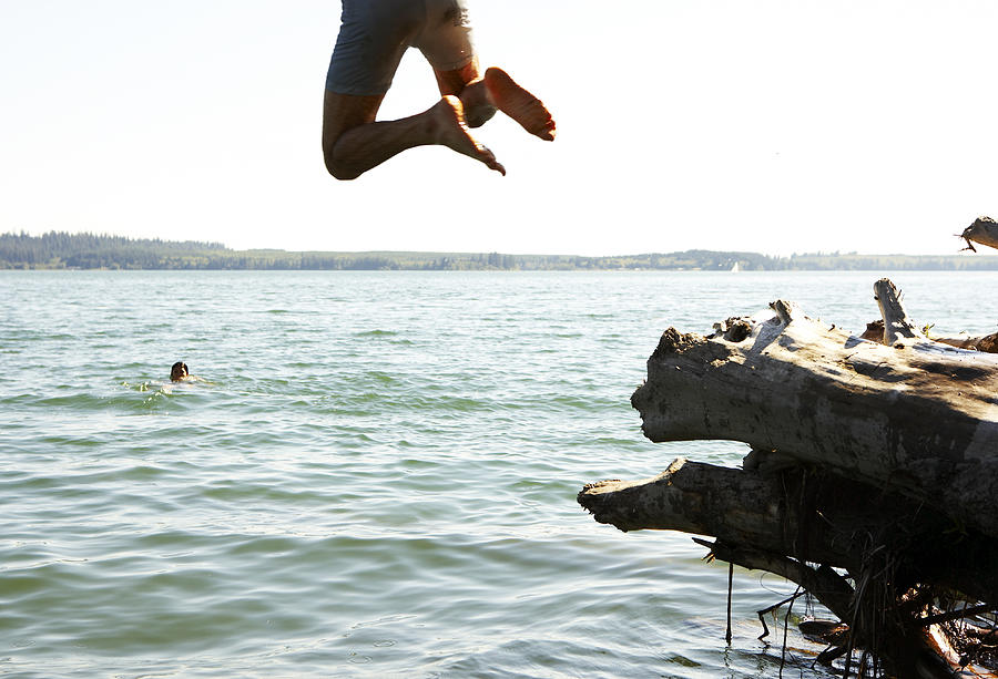 Young man jumping into lake Photograph by Thomas Northcut