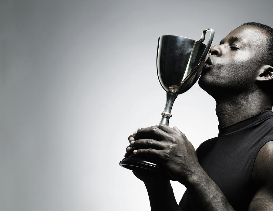 Young man kissing trophy, close-up Photograph by Flashpop