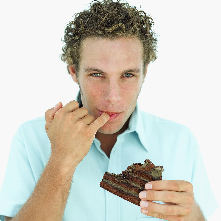 Young man licking chocolate off his finger Photograph by George Doyle