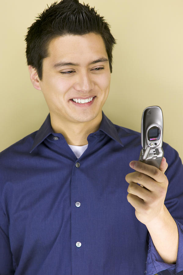 Young man looking at a mobile phone Photograph by Photodisc