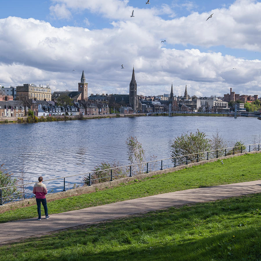 Young man looking at the city of Inverness from the bank of the  Photograph by David L Moore