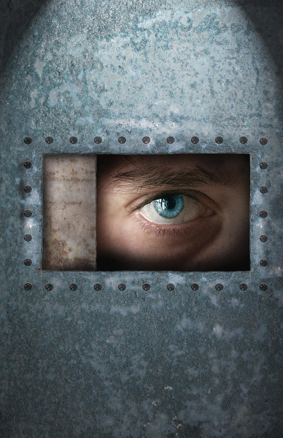 Young man looking through window in metal enclosure, close-up of eye Photograph by Regine Mahaux