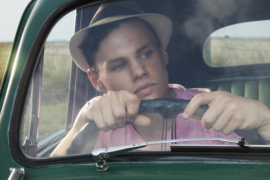 Young man looking through windscreen of vintage morris minor Photograph by Elke Meitzel