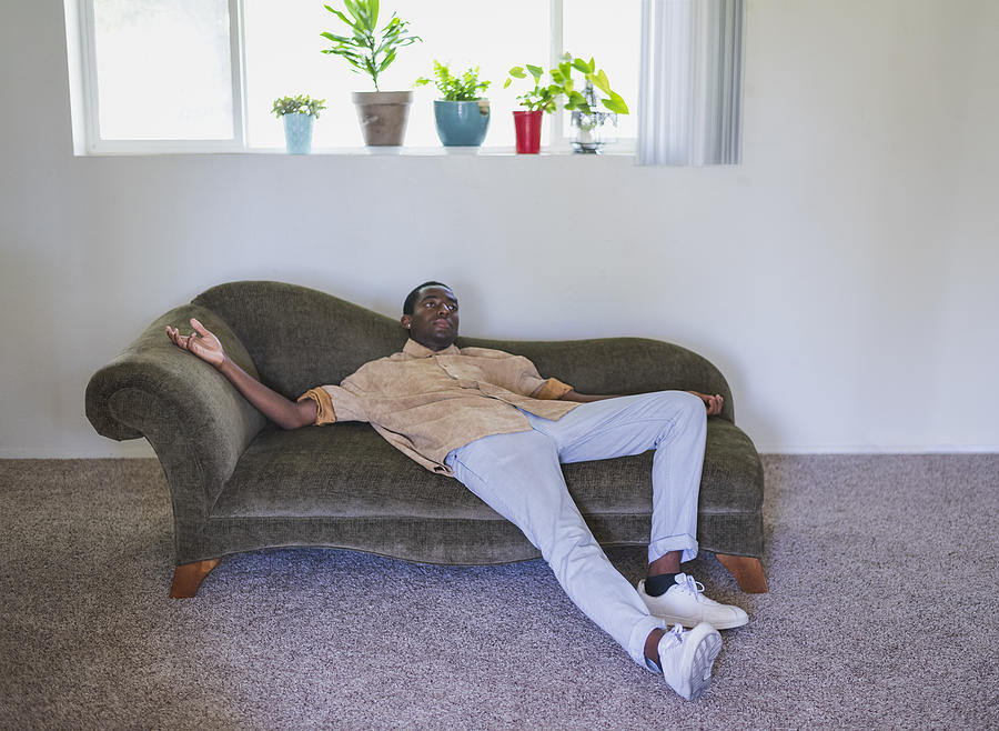 Young man lounging on sofa Photograph by Tony Anderson