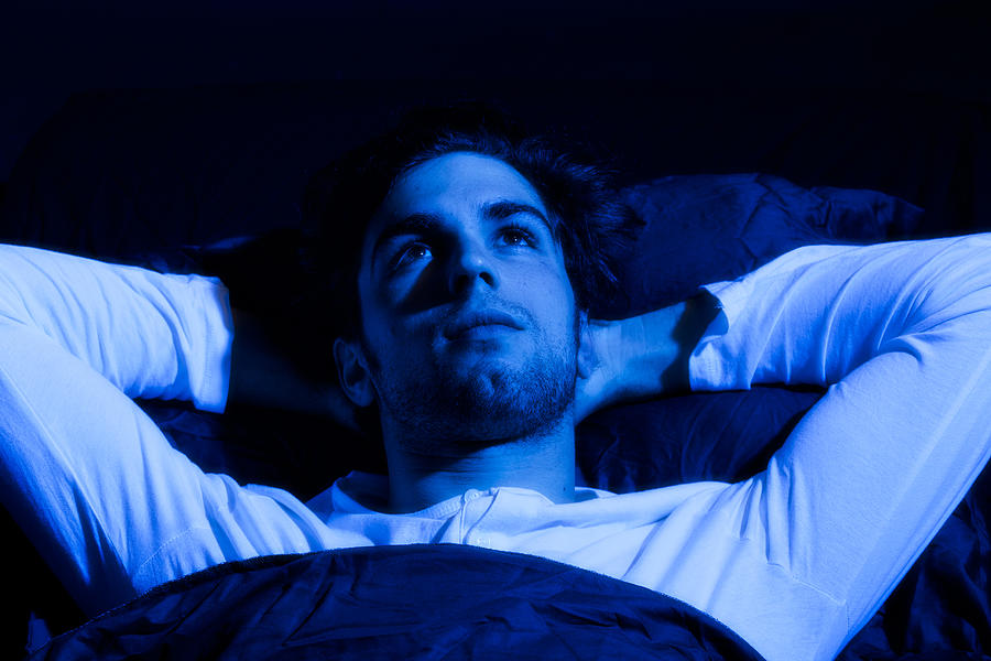 Young man lying awake Photograph by Opla