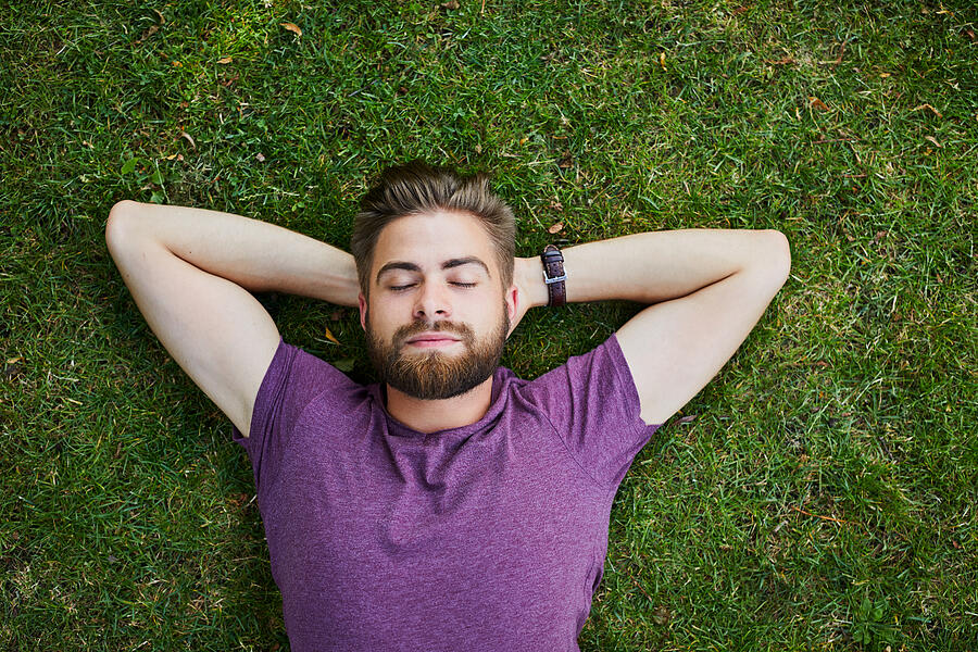 Young man lying on ground in park outdoors with eyes closed Photograph by BartekSzewczyk