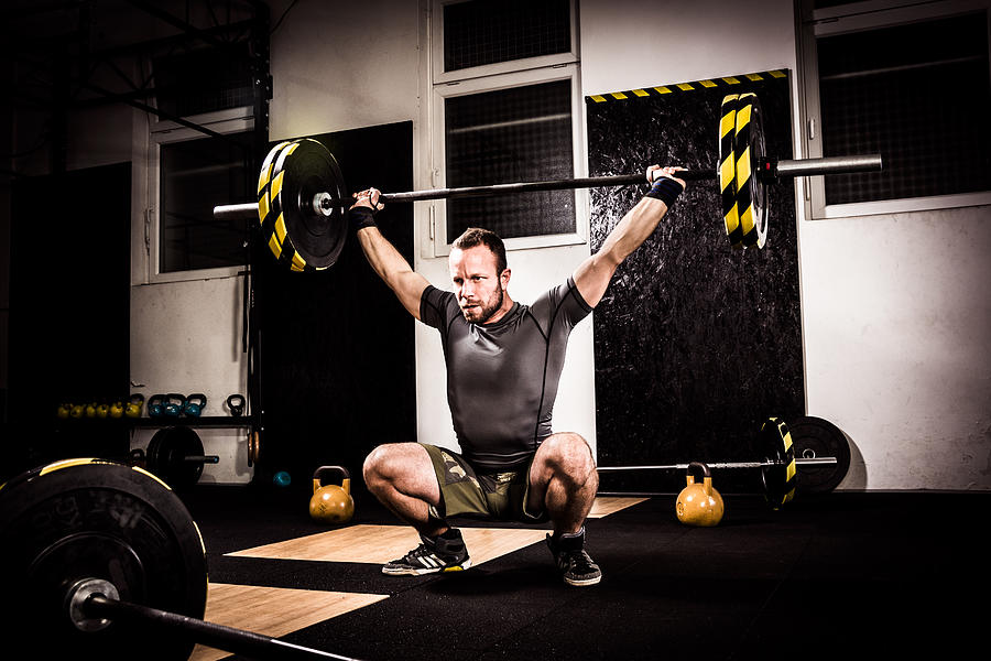 Young man on cross training lifting weights Photograph by Zoran Kolundzija
