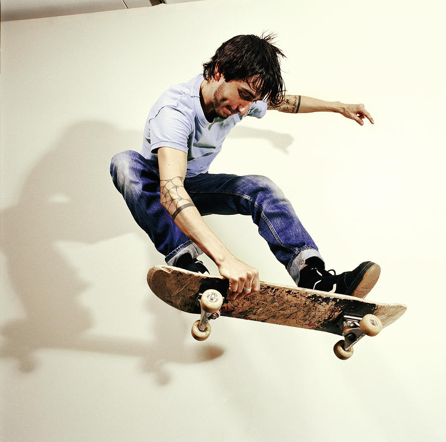 Young man performing skateboard trick, mid-air Photograph by Devon Strong