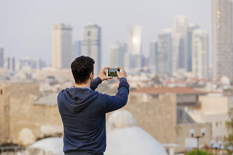 Young man photographing Tel Aviv skyline, Israel Photograph by Alexander Spatari