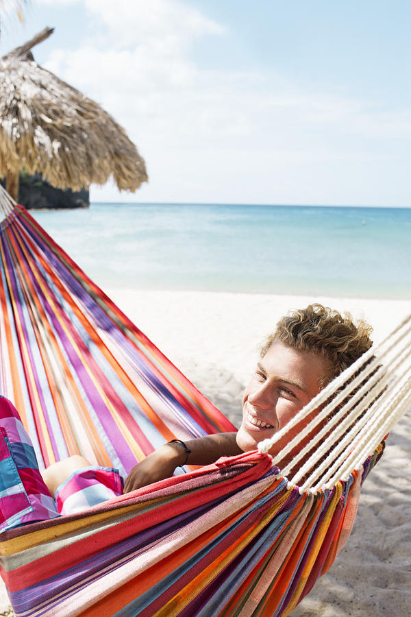 Young man relaxing in hammock on beach Photograph by Felix Wirth