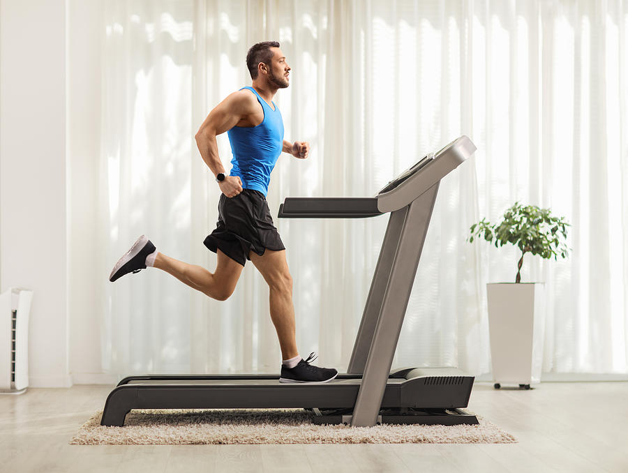 Young man running on a treadmill at home Photograph by Ljupco