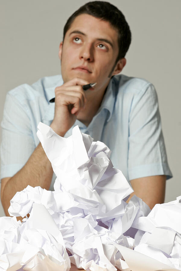 Young man sitting at desk with crumpled paper Photograph by Loop Delay