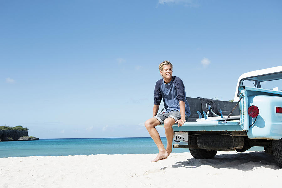 Young man sitting on trailer on beach Photograph by Felix Wirth