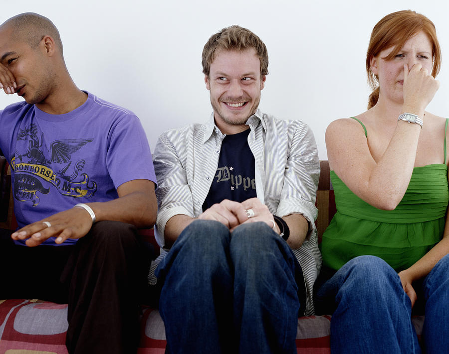 Young man, smiling, sitting between man and woman holding noses Photograph by Digital Vision