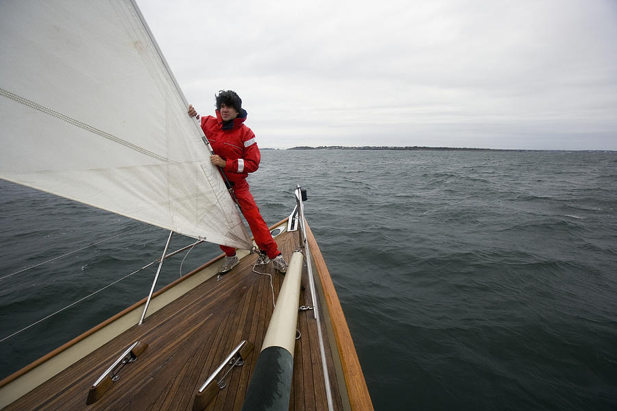 Young man standing in racing yacht Photograph by Jeff Randall