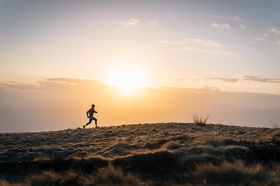 Young man trail runs up mountain at sunrise Photograph by AscentXmedia