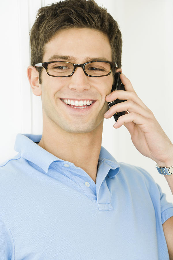Young man using telephone, smiling Photograph by Pando Hall