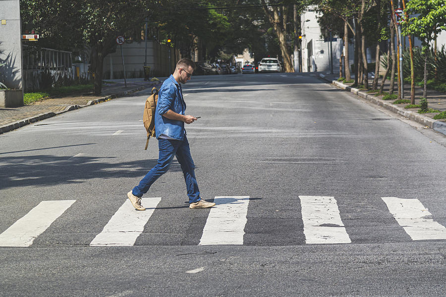 Young man walking at crosswalk on a Sao Paulos street Photograph by Wsfurlan