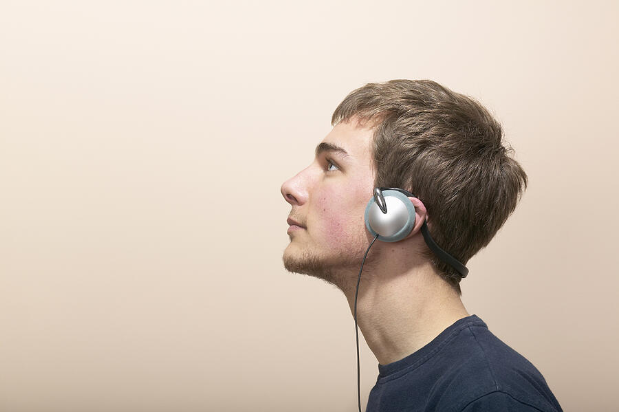 Young man wearing headphones, profile, close-up Photograph by Richard Drury
