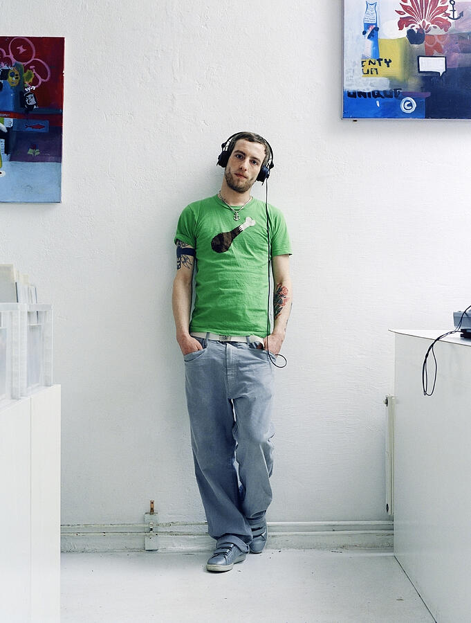 Young man wearing headphones with hands in pockets, portrait Photograph by Joos Mind