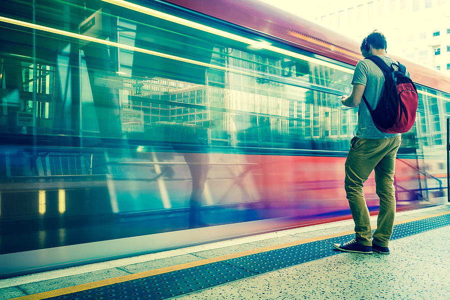 Young man with backpack and headphones waiting for train Photograph by Adam Petto
