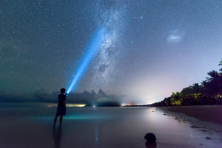 Young Man with Flashlight Stands on the Beach While Watching Galaxy , Cairns, Australia Photograph by AlexTIZANO