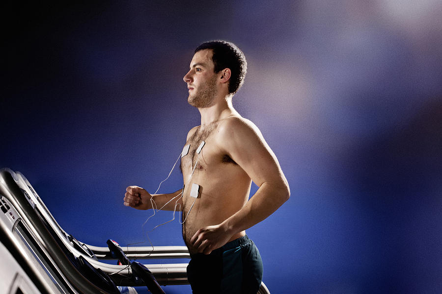 Young man with heart rate monitor running on gym treadmill in altitude centre Photograph by Vincent Starr Photography